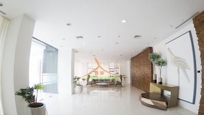 A spacious, modern living area with a large sofa, a coffee table, and a decorative wall with a bird mural. There are potted plants and a wooden bench. - Your Dream Home at Abreeza Davao (Davao)