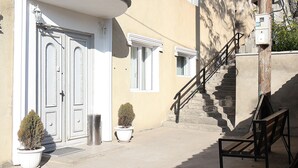 Un edificio con una entrada curva, una escalera y un banco en el exterior.