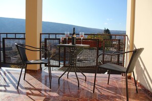 A balcony with a table and chairs, a bottle, and two glasses. - Boutique Hotel Dany (Tbilisi)