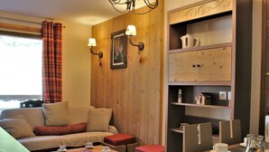 Ein gemütliches Zimmer mit einer Couch, einem kleinen Tisch und einem Schrank mit Regalen.