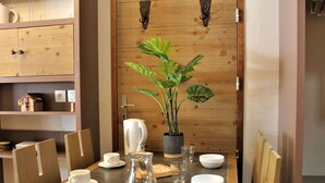 Ein Holzespeisetisch mit Stühlen, einer Topfpflanze, einer Karaffe und Schüsseln.