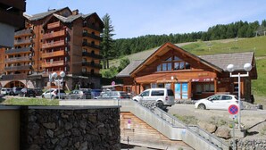 Eine Berglodge mit Holzfassade, Steinwand und Parkplatz mit Autos.