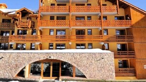 Ein mehrstöckiges Hotel mit hölzernen Balkonen und einem Eingang mit steinernen Rundbögen.