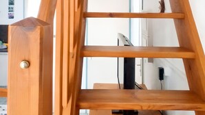 Una escalera de madera con barandilla, que lleva a una plataforma nivelada.