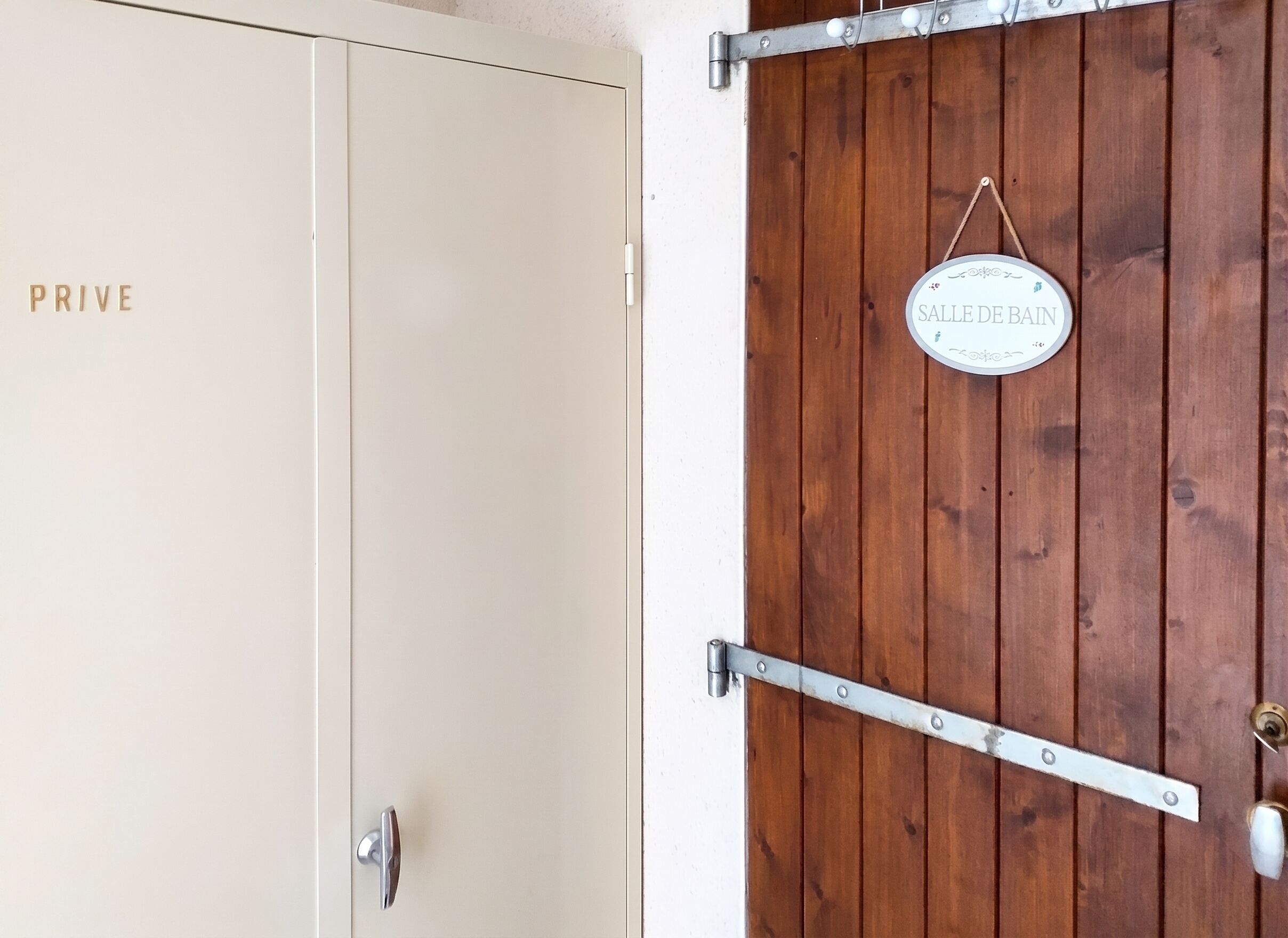 A door with a sign that reads 'SALLE DE BAIN' and a metal handle.