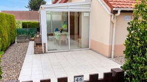 Un patio con puerta de vidrio, pared de ladrillo y valla de madera con el número 46.