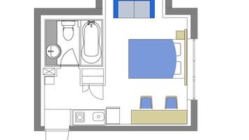A floor plan of a hotel room with a bed, a bathroom, a desk, and a small kitchenette.
