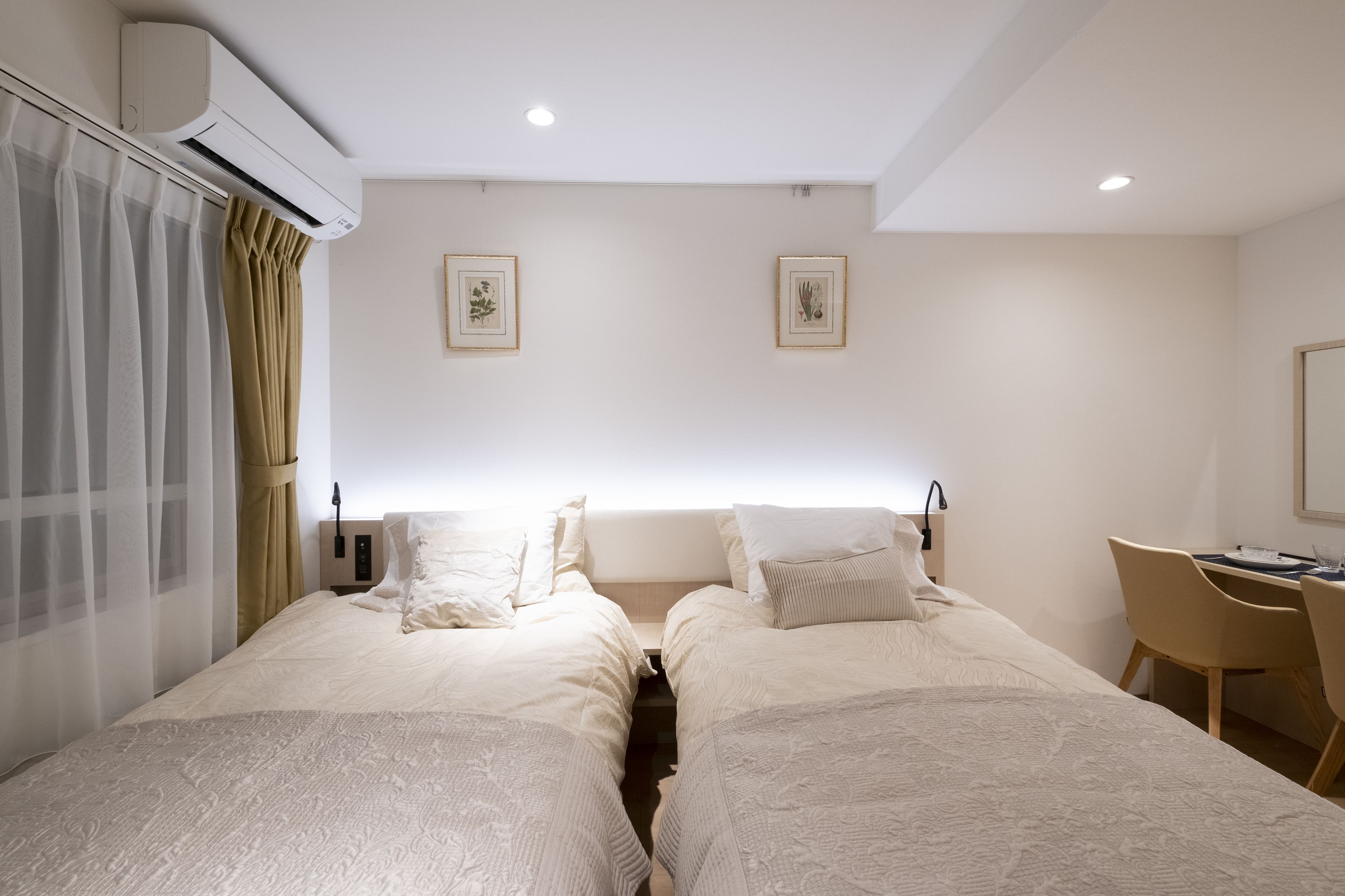 A hotel room with two beds, a desk, and a chair.