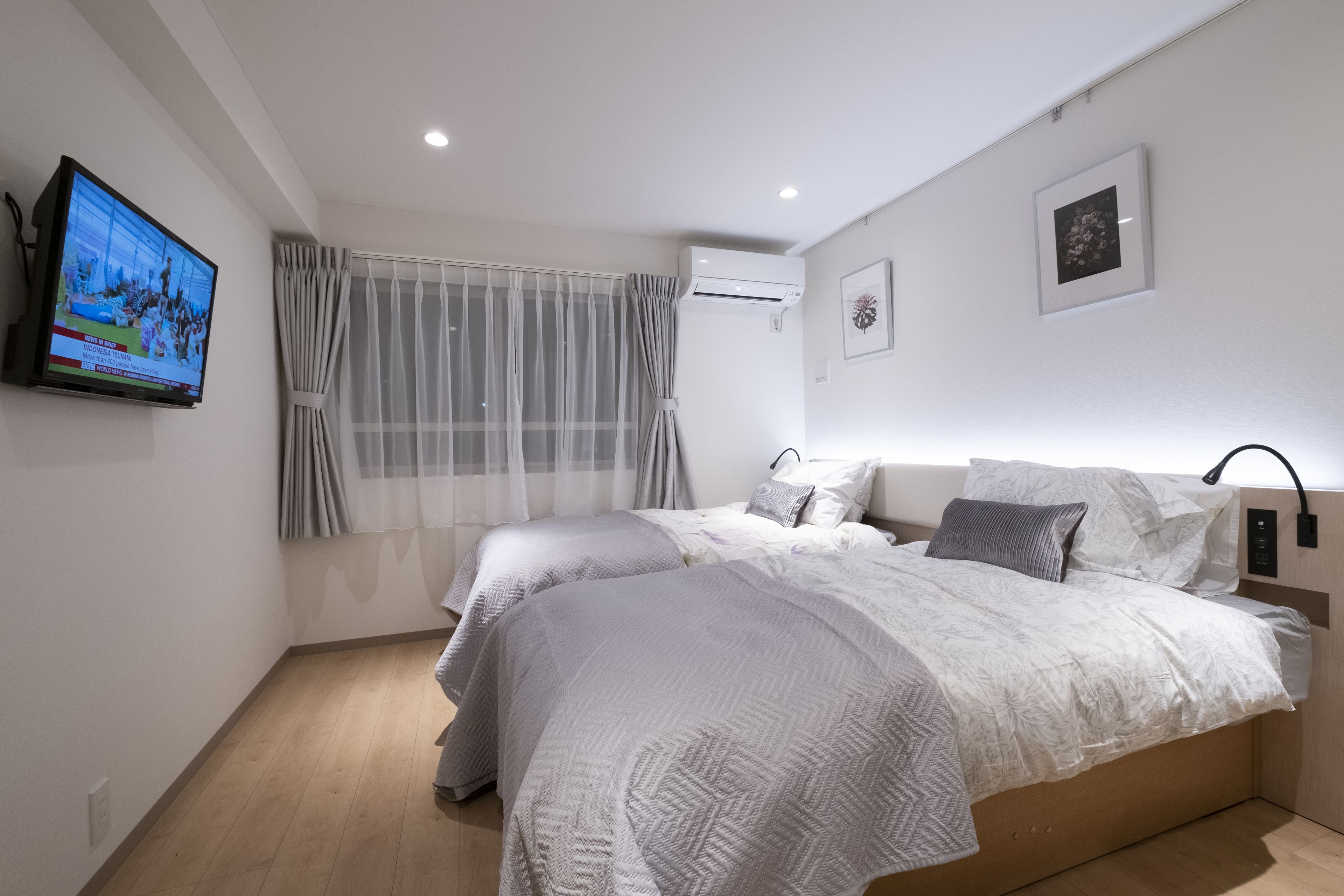 Un dormitorio moderno con dos camas, un televisor y un equipo de aire acondicionado.