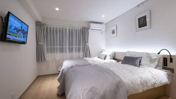 Un dormitorio moderno con dos camas, un televisor y un equipo de aire acondicionado.