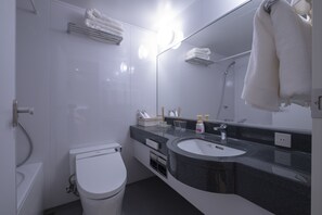 A modern bathroom with a white toilet, a sink with a dark countertop, and a large mirror. - STUDIO INN NISHISHINJUKU (Tokyo)
