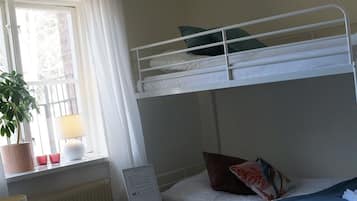 Habitación con literas, una ventana, una mesita, una lámpara y un radiador.