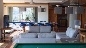A modern living room with a sofa, a pool table, and a dining area with chairs. - Villa Sofia (La Spezia)
