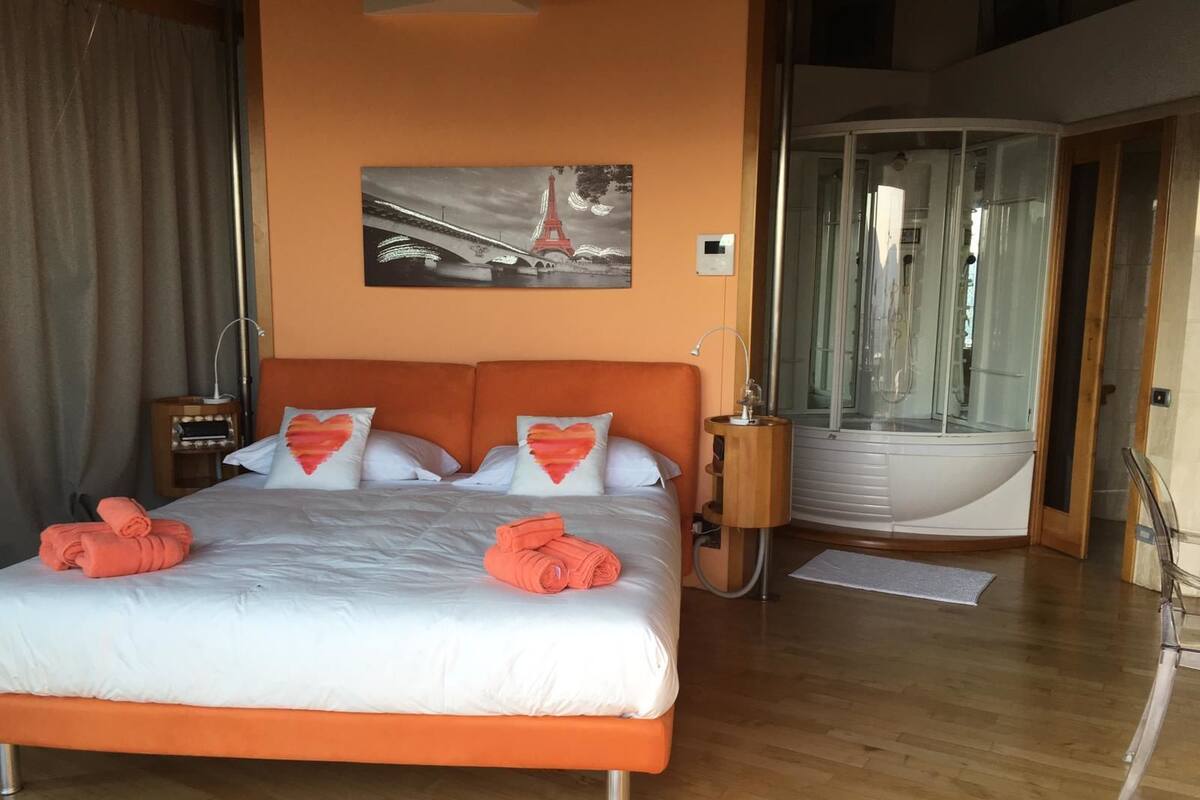 Hotelkamer met een bed, een schilderij van de Eiffeltoren, een jacuzzi en houten vloeren.