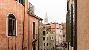 Un canal étroit dans une ville européenne historique, avec des bâtiments de chaque côté, un pont et une tour en arrière-plan.