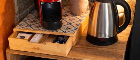 A compact kitchen setup with a coffee maker, a kettle, and a drawer organizer on a wooden surface.