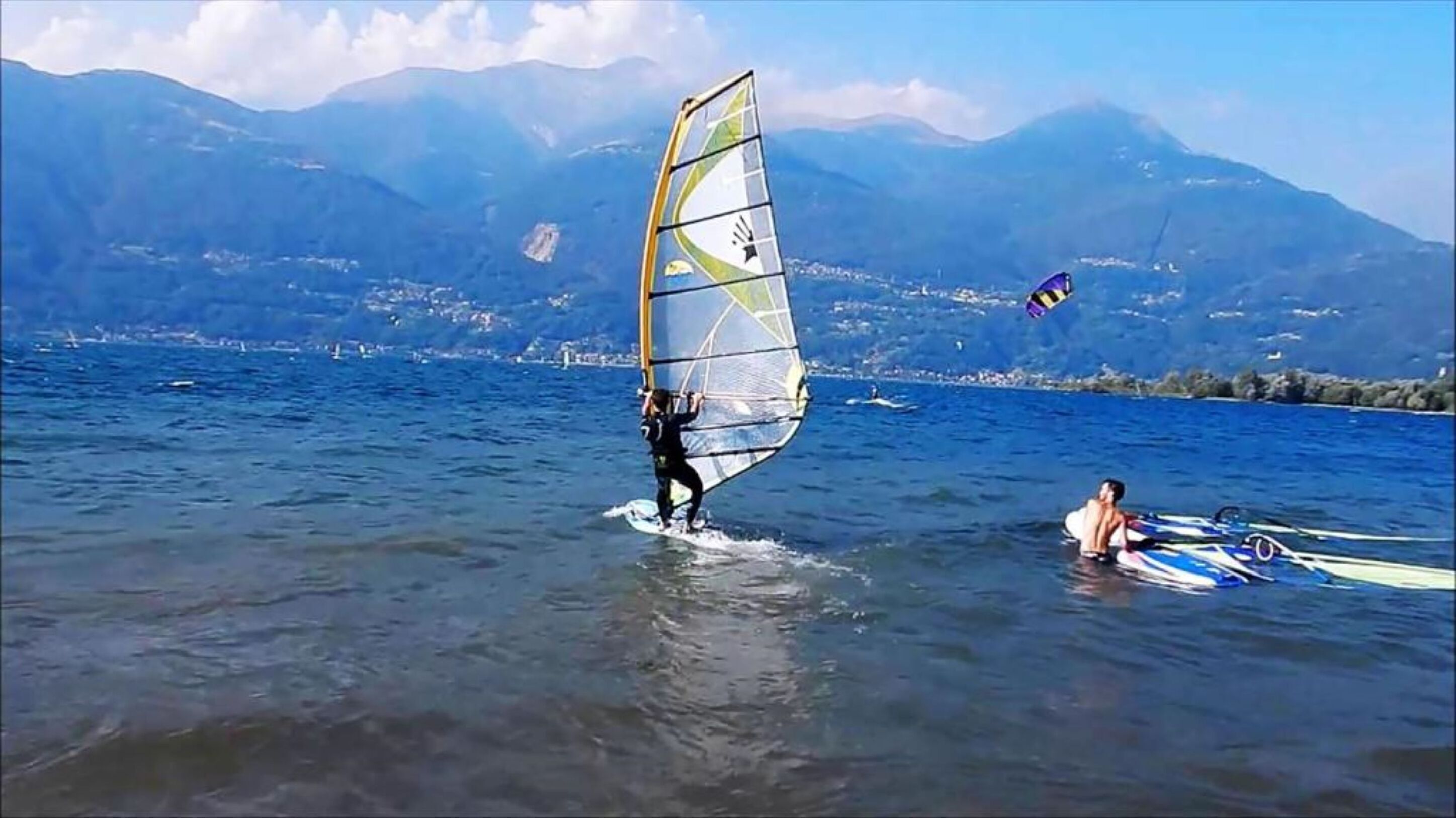 A person windsurfing on a lake with mountains in the background.
