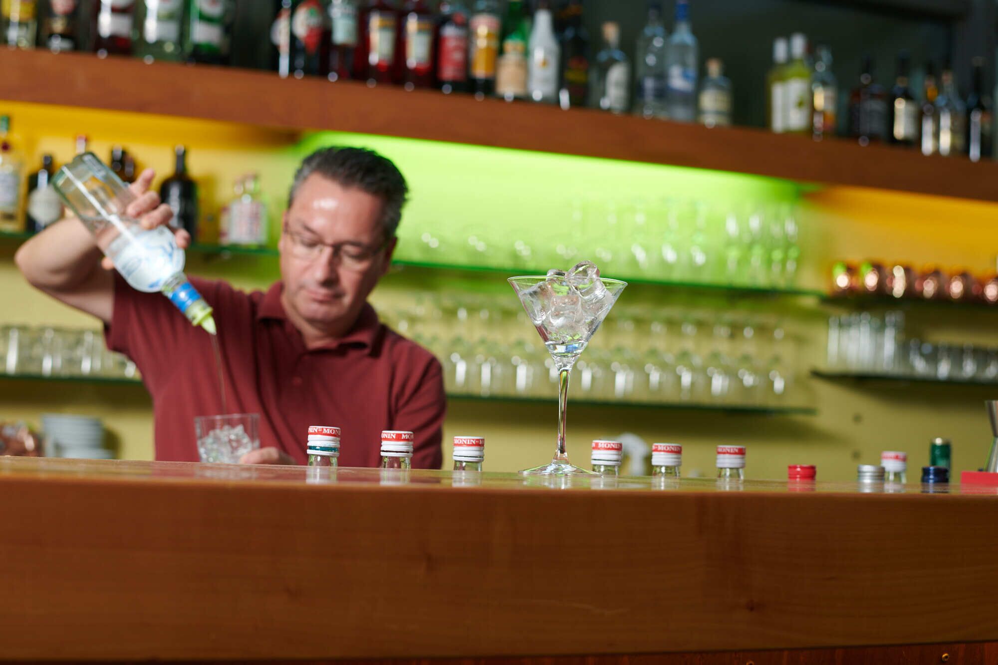 Ein Barkeeper gießt ein Getränk in ein Martini-Glas.