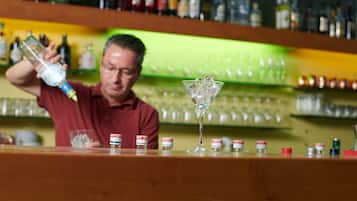 Ein Barkeeper gießt ein Getränk in ein Martini-Glas.