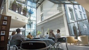 A modern indoor space with a glass ceiling, seating areas, and potted plants. - Hotel Berchtold (Burgdorf)