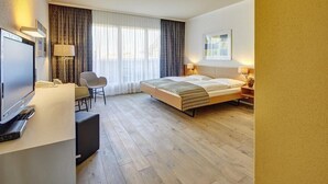 A hotel room with a bed, a desk with a computer, a chair, and a TV. - Hotel Berchtold (Burgdorf)