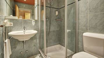 A modern bathroom with a glass-enclosed shower, a white sink, and a toilet.