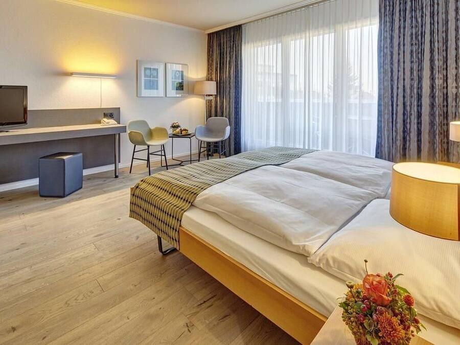 Una habitación de hotel con una cama, un escritorio, un televisor y una silla.