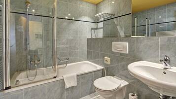 Une salle de bain moderne dotée d’une douche à parois de verre, d’une baignoire sur pieds, de toilettes et d’un lavabo.