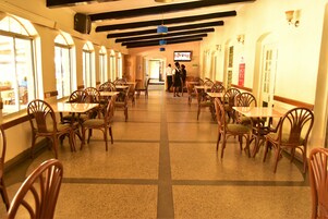 Un restaurante con sillas y mesas de madera, una pantalla de televisión y piso de baldosas.