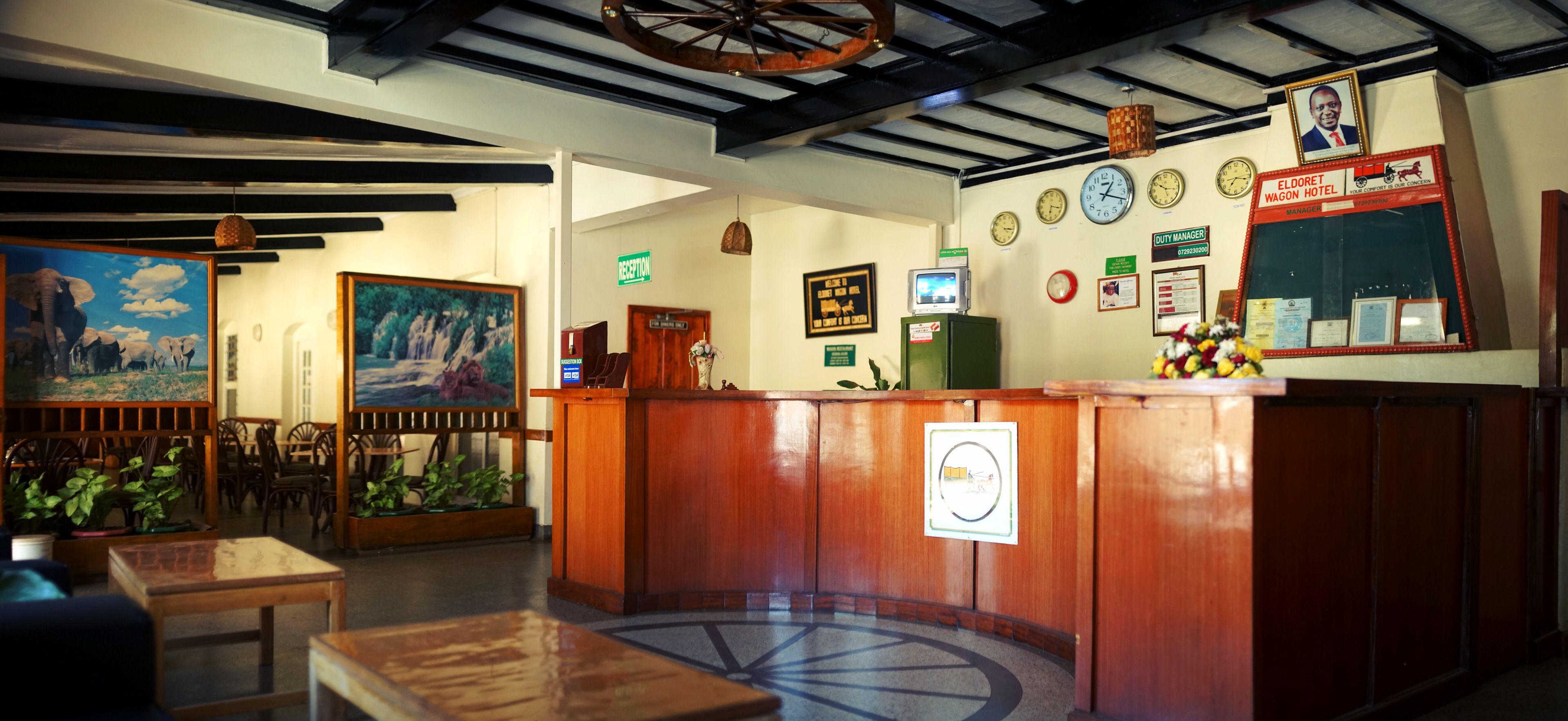 A reception area with a wooden counter, a reception desk, a clock, and a framed portrait on the wall.