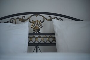 A bed with a black metal headboard featuring ornate designs and two white pillows.
