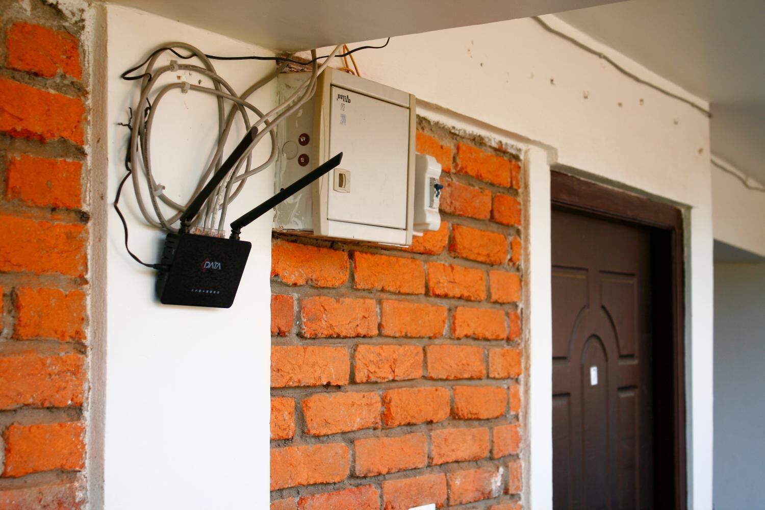 A brick wall with electrical wiring and a power box.