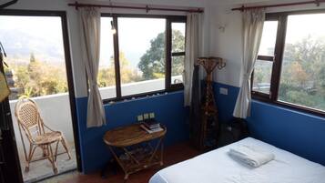 A room with a bed, a small table, a chair, and a window with curtains.