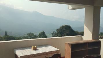Un balcón con mesa y sillas, con vistas a un paisaje montañoso.