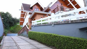 A residential building with a sloped roof, a white fence, and a stone pathway leading to the entrance.
