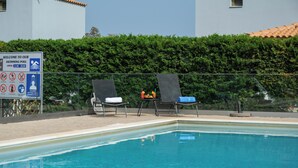 A swimming pool with lounge chairs and a sign indicating the pool's opening hours. - Spedion Villa Gytheio (East Mani)