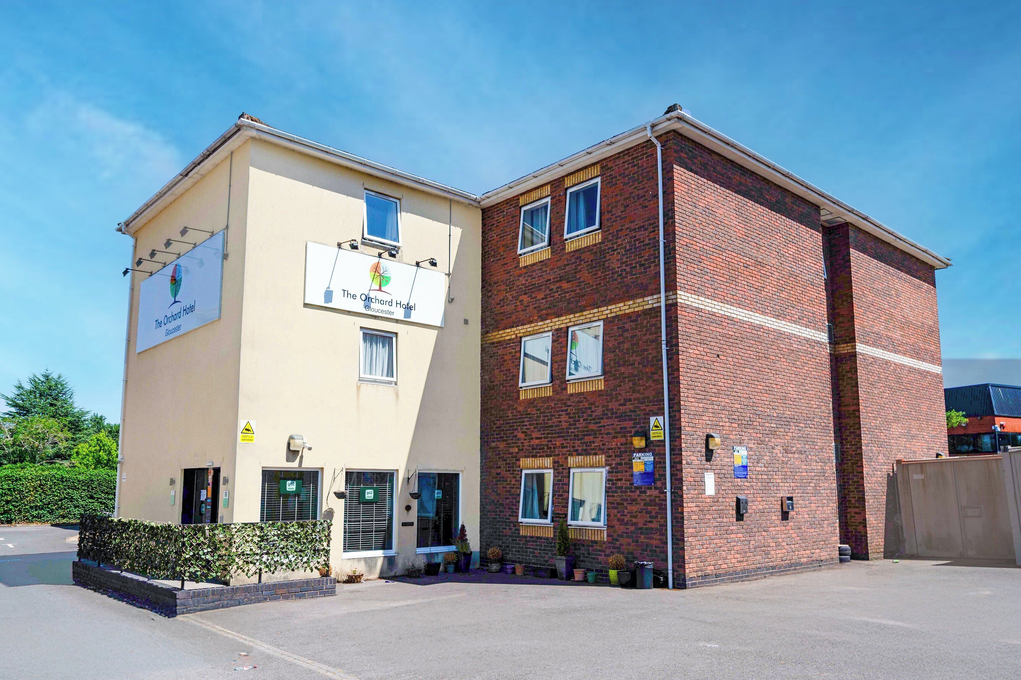 A two-story building with a sign for 'The Orchard Hotel' and 'The Orchard Hotel' on the side.