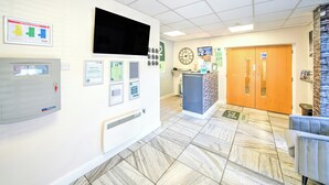 A reception area with a digital display, framed certificates, a clock, and a reception desk. - the orchard hotel (Quedgeley)