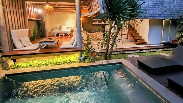 A modern outdoor pool area with lounge chairs and a dining table, surrounded by a well-maintained garden and a staircase leading to an upper level. - WOODEN Home Top LOCATION in Seminyak Near Beach, Shops, Restaurants (seminyak)