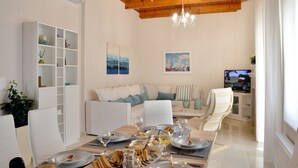 A dining area with a wooden table set for a meal, white chairs, and a white cabinet with shelves. - Villa Despina in Kissamos (Kissamos)