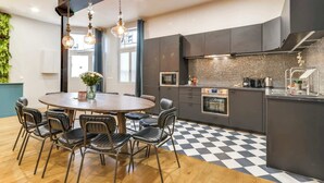 A modern kitchen with a central island, dark cabinetry, and a checkered floor.