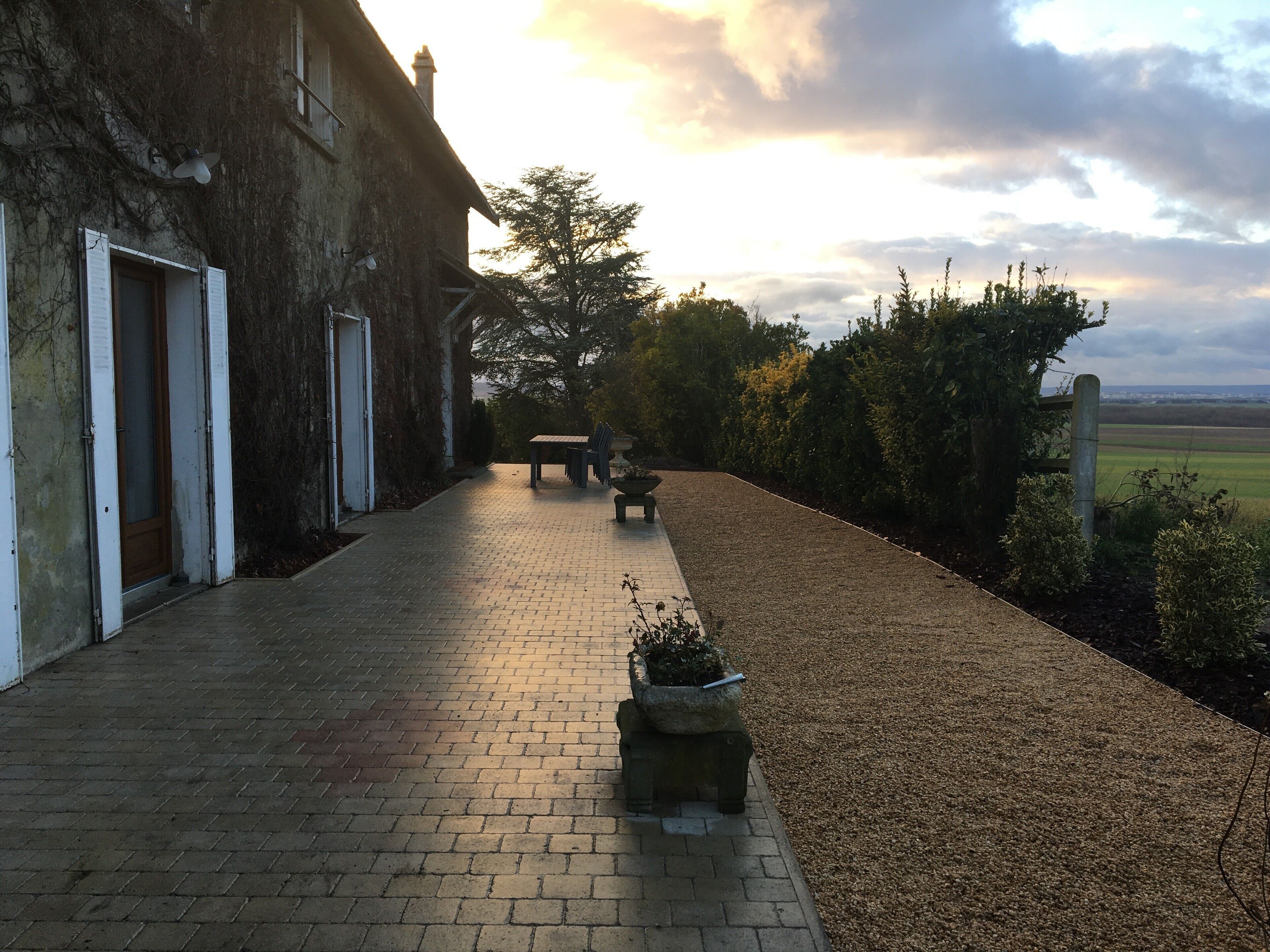 Un sendero pavimentado que conduce a un edificio con una puerta y un banco.