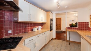 A modern kitchen with white cabinets, a stove, and a tiled backsplash. - Portobello House Newark (Newark)