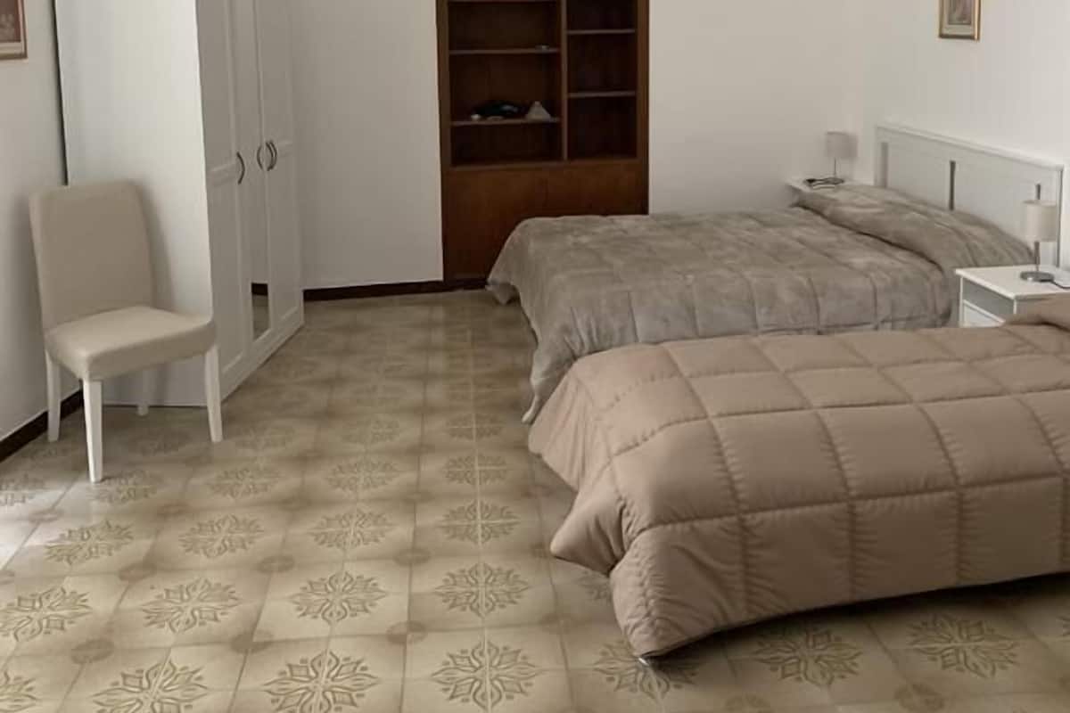 A bedroom with a bed, a chair, a wardrobe, and a hanging lamp.