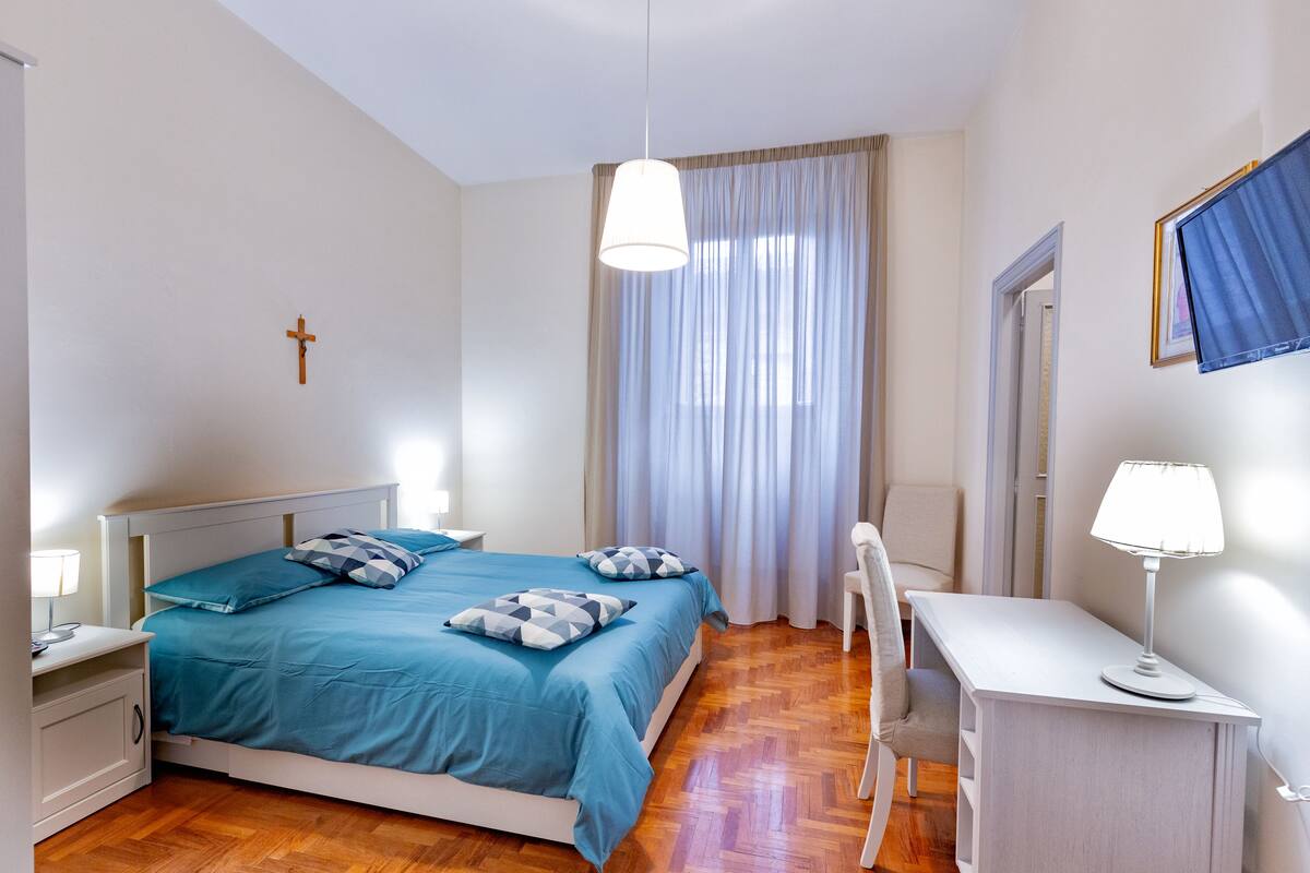 A bedroom with a bed, bedside tables, a desk, and a chair.
