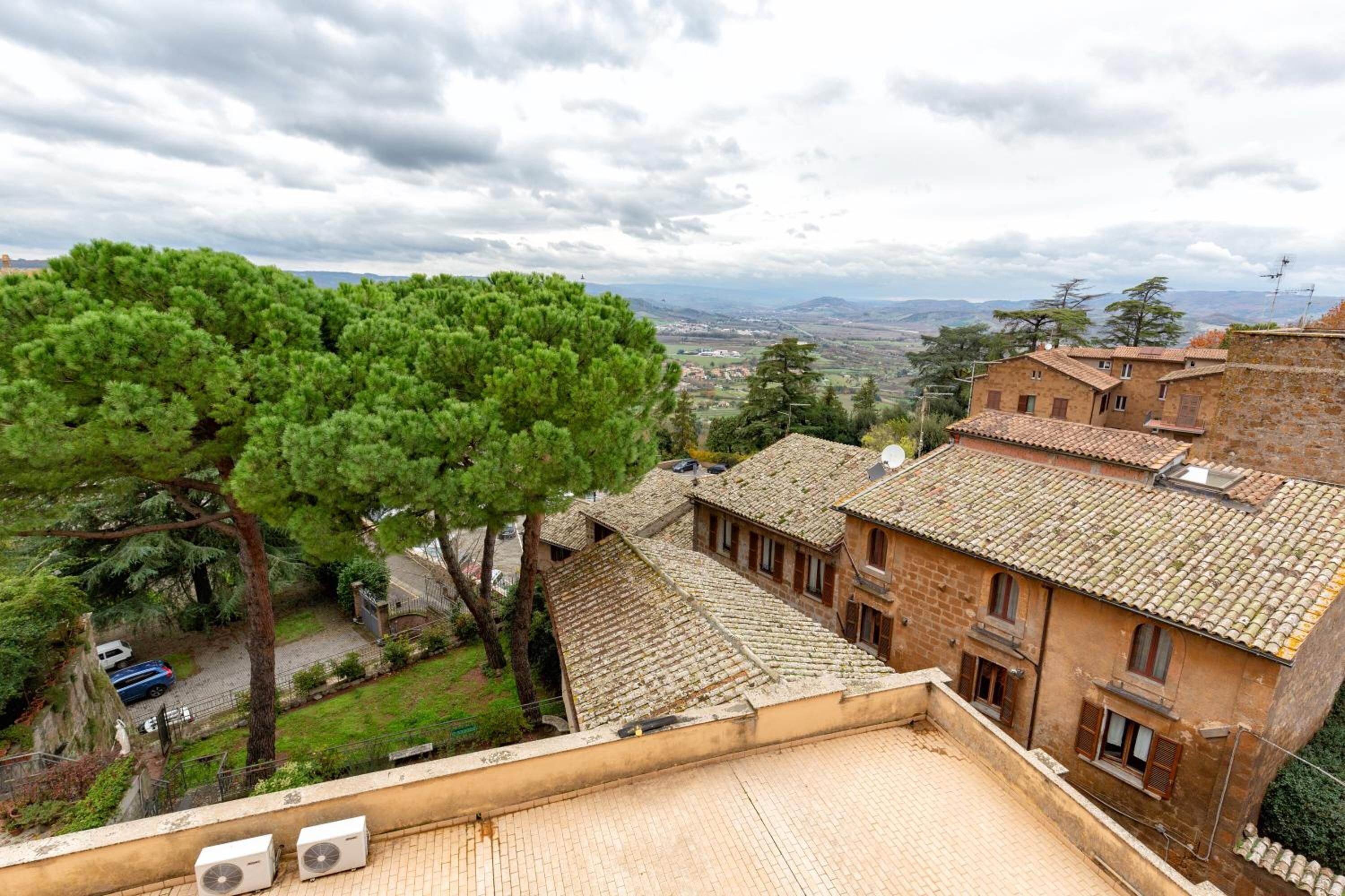 A traditional building with a tiled roof, a courtyard, and a view of a distant landscape.