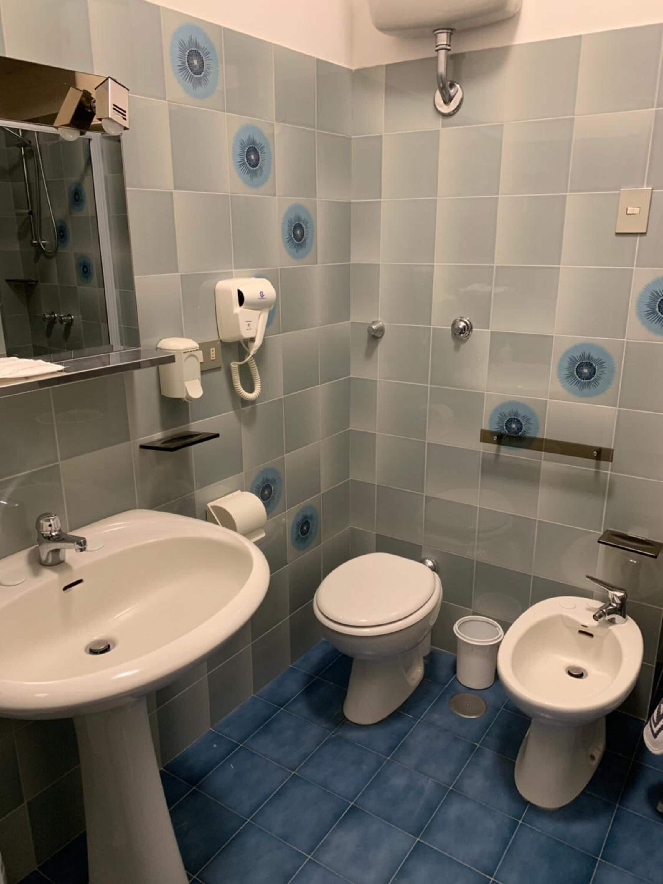 Un baño con lavamanos, inodoro, bidé y un espejo.