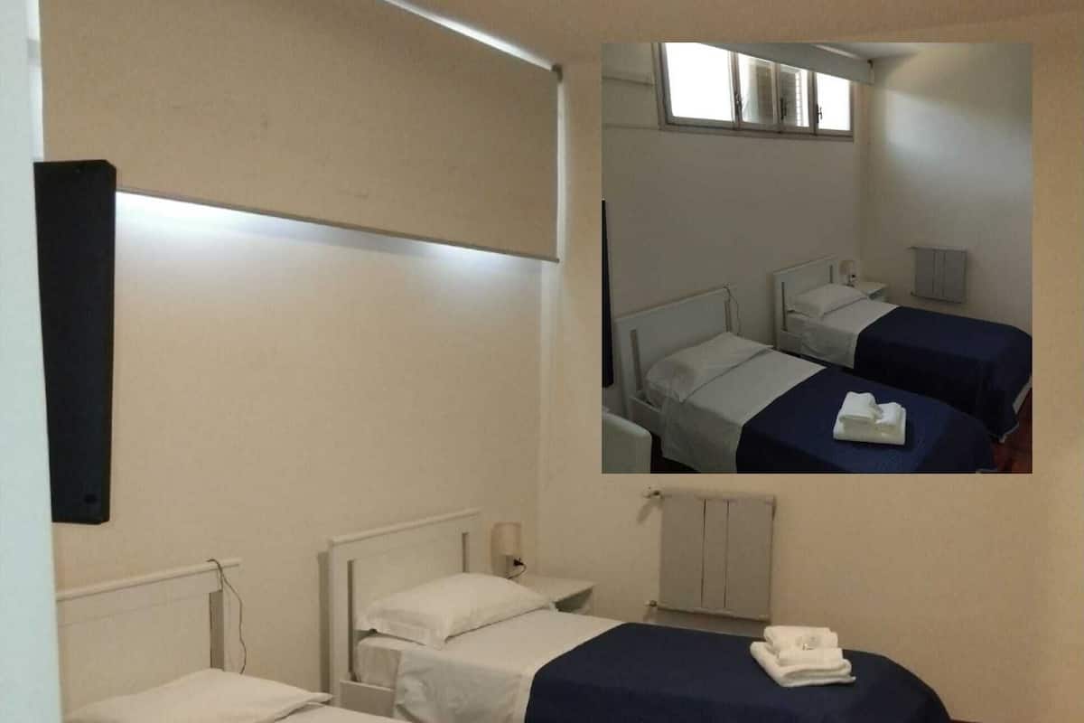 A room with two single beds, a small table, and a mirror.
