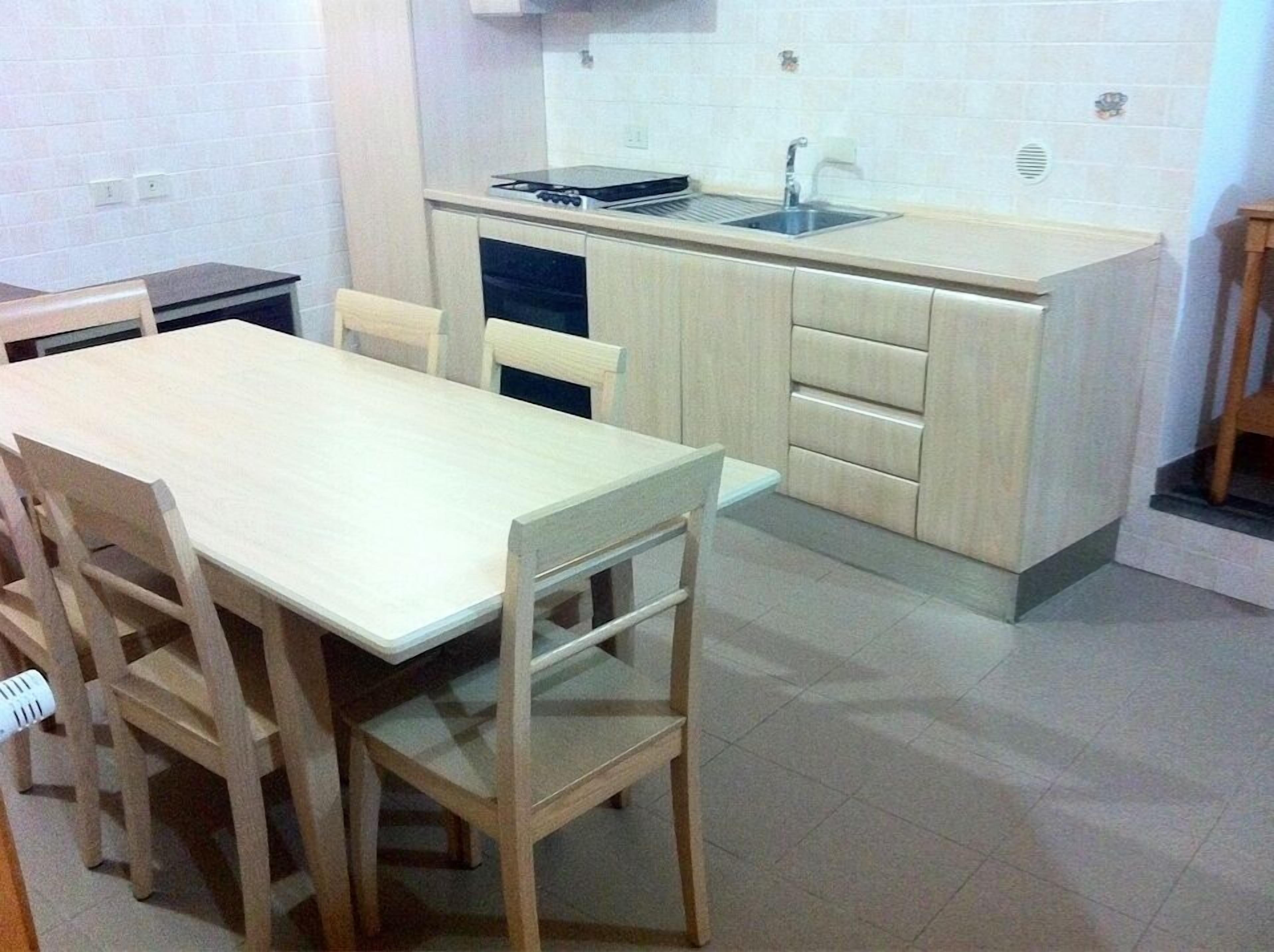 Cocina compacta con comedor, que incluye una pequeña isla, un fregadero y muebles básicos.