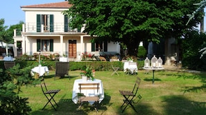 A villa with a garden patio featuring outdoor seating and birdcages. - Villa Le Rose (Cavour)
